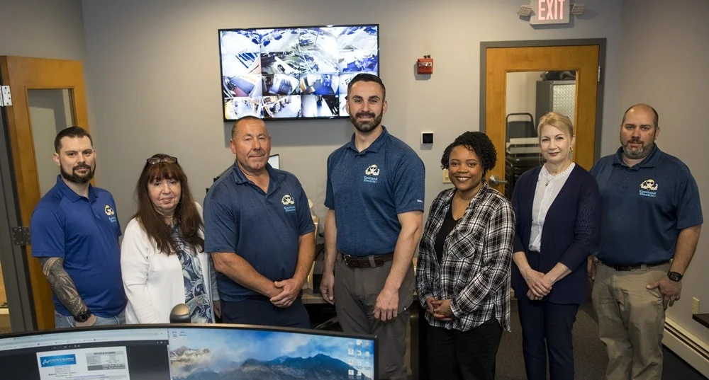 The team of Eastland employees standing in the office in front of a TV screen, posing for a picture