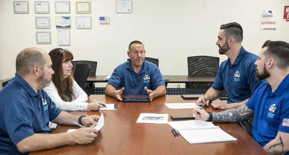 The Eastland Electric team sitting together at a morning meeting at a conference table